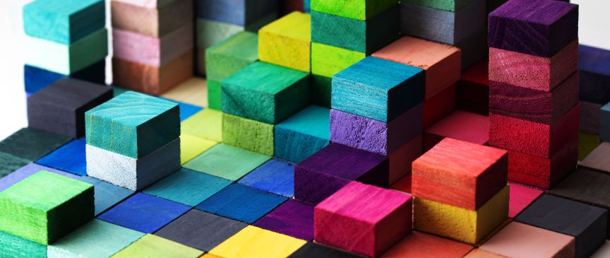 Bunte Holzwürfel in verschiedenen Farben sind zu einem dreidimensionalen Muster in unterschiedlichen Höhen angeordnet.