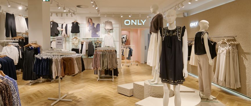 Modeboutique „Only" mit zwei Schaufensterpuppen, Kleiderständern und hellem Holzboden unter Strahlerbeleuchtung.