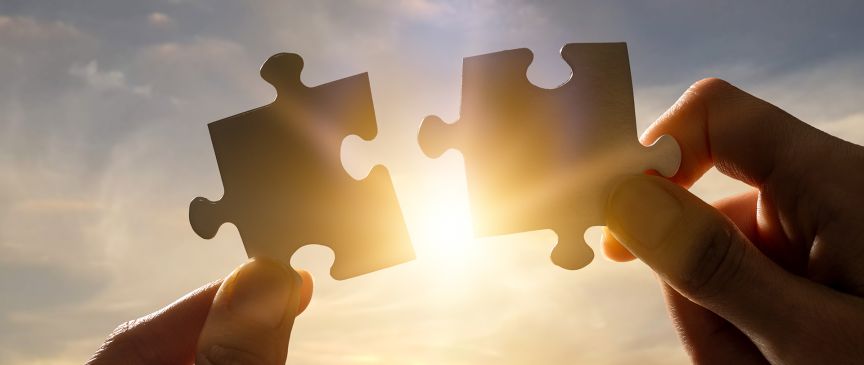 Zwei Hände und zwei Puzzleteile, und in der Mitte der Sonnenschein.