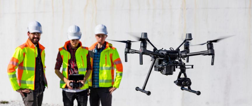 Drei Männer fliegen eine Drohne.