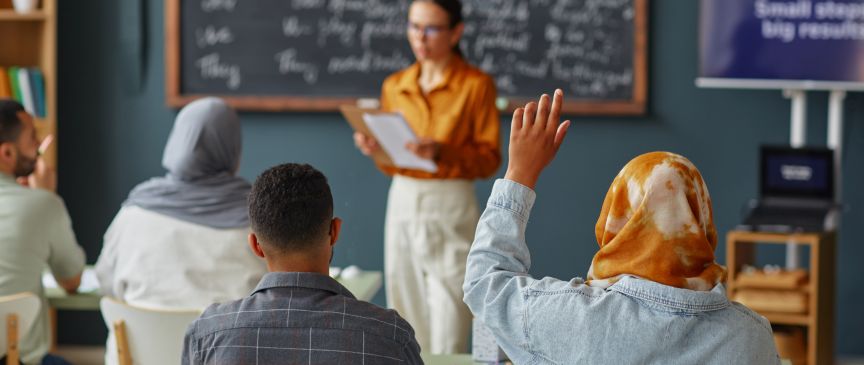 Lehrerin und vier Schüler und Schülerinnen in einem Klassenzimmer.