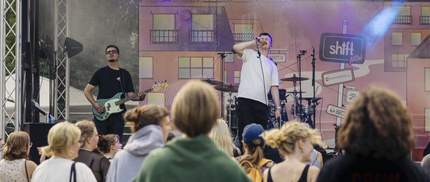 Menschenmenge beim Konzert vor einer Bühne, Sänger auf der Bühne