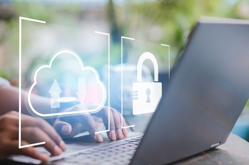 Hände tippen auf Laptop-Tastatur; digitale Overlays zeigen Cloud-Upload-Symbol und geöffnetes Schloss.