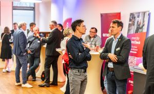 Personen unterhalten sich bei einer Veranstaltung. Im Hintergrund rote Roll-ups mit Aufschrift „enercity".