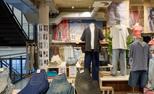 BDG Jeans Store mit Mannequins in Jeans und T-Shirts, Jeansstapeln auf Holzregalen und Werbeplakaten an der Wand.