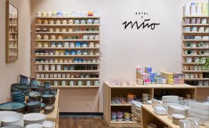 Keramikgeschäft „Motel a Miio" mit bunten Tassen und Tellern auf Holzregalen an weißer Wand.