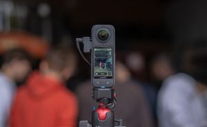 Eine Insta360-Kamera auf einem Ulanzi-Stativ, im Vordergrund scharf, im Hintergrund unscharf Personen.