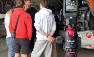 Ulanzi-Stativ mit 360°-Kamera im Vordergrund, dahinter vier Personen in einer Werkstatt.