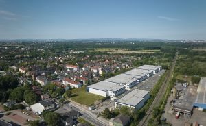 Luftaufnahme einer deutschen Kleinstadt mit Wohnhäusern, Industriegebäuden, Bahngleisen und umliegenden Grünflächen.