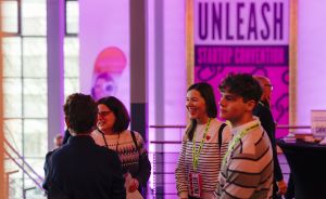 Vier Personen mit Namensschildern unterhalten sich in einem Veranstaltungsraum vor einem "Unleash Startup Convention"-Banner.