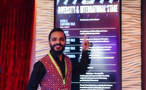 Mann mit Bart und roter Weste zeigt auf Display „Diversity & International Stage" bei UNLEASH-Konferenz.