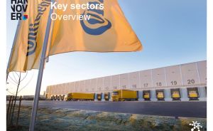 Gelbe Continental-Flaggen vor einem Logistikzentrum mit nummerierten Laderampen und gelben LKW, Region Hannover.