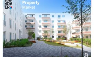 „Innenhof eines weißen Mehrfamilienhauses mit Balkonen, Bepflanzung und Sitzbereichen, Text: Property Market Hannover"