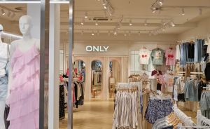 Innenansicht eines ONLY-Modeshops mit Kleiderständern, Mannequin in rosa Kleid und heller Holzboden-Ausstattung.