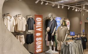 Modeboutique "Only & Sons" mit Mannequins in Freizeitkleidung, Kleiderständern und beleuchteten Tracking-Spots an Betondecke.