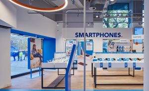 Modernes Smartphone-Geschäft mit blauen Displays, Geräten auf Tischen, großem Schaufenster und „SMARTPHONES"-Schriftzug an der Wand.