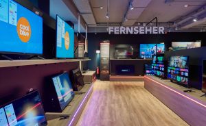 Coolblue-Elektronikgeschäft mit Fernseher-Abteilung: Mehrere TVs auf Regalen, LED-Beleuchtung am Boden, TCL-Display im Hintergrund.