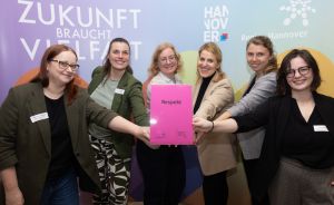 Sieben Frauen halten gemeinsam eine pinke Mappe mit der Aufschrift „Respekt" vor einem Hannover-Banner.