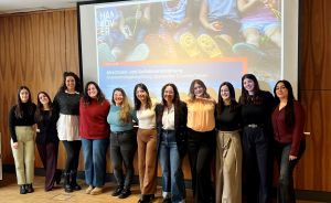 11 Frauen stehen nebeneinander und lächeln.