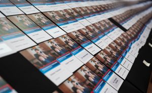 Viele gedruckte Namensschilder mit Fotos und Text liegen in Reihen auf einer schwarzen Unterlage.