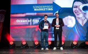 Zwei Männer stehen auf einer Bühne vor einer Leinwand mit „Sonderpreis Marketing – Ocean of Fits". Der linke hält eine Urkunde.