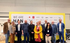 Gruppe von etwa 11 Personen posiert vor einem gelb-schwarzen Banner mit der Aufschrift „We Are Hannover".