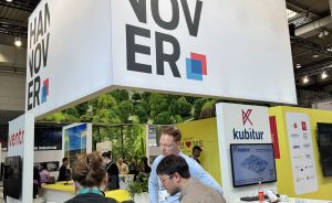 Messestand "Hannover" mit großem weißem Würfel-Logo, darunter Besucher im Gespräch, rechts "kubitur"-Stand.