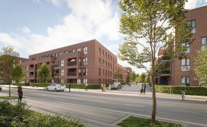 Mehrstöckige Backsteingebäude an einer Straße mit Bäumen, geparkten Autos und Fußgängern bei bewölktem Himmel.