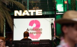 Veranstaltungsort mit Leuchtschrift „NATE" und Bildschirm mit Logo „Fireabend Hannovr", Menschen im Vordergrund.
