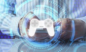 Person in gestreiftem Hemd hält Tablet; darüber blaues digitales HUD mit weißem Gamecontroller-Symbol.
