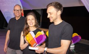 Zwei Männer und eine Frau mit einem Preis in der Hand.