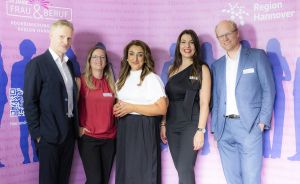 Zwei Männer und drei Frauen vor einer rosa Wand.