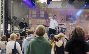 Menschenmenge beim Konzert vor einer Bühne, Sänger auf der Bühne