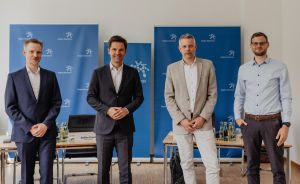 Vier Männer stehen vor blauen Rollup-Bannern mit der Aufschrift „Region Hannover" in einem Besprechungsraum.