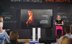 Frau präsentiert beim #SmartStartAward KPMG Innovate vor Publikum. Slide zeigt "Problem: Es existiert kein niedrigschwelliges Bauchtanzformat!"