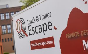 Weißer Truck mit Logo „Truck & Trailer Escape" und Website truck-escape.com, im Hintergrund ein Gebäude.