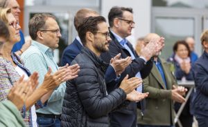Gruppe von Erwachsenen applaudiert gemeinsam bei einer Veranstaltung im Freien.