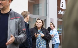 Mehrere Personen stehen vor einem Shopify-Gebäude und unterhalten sich. Eine Frau gestikuliert beim Sprechen.