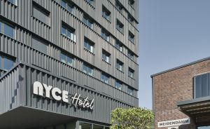 Modernes graues Hochhaus mit Schriftzug „NYCE Hotel", daneben Backsteingebäude mit Schild „Weidendamm 2", Terrasse.