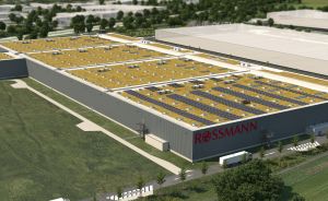 Luftbildansicht eines großen Rossmann-Lagergebäudes mit begrüntem Dach, Solaranlage und umliegender Grünfläche.