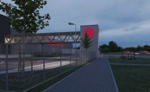 Industriegebäude bei Dämmerung mit beleuchtetem roten Firmenlogo, Metallzaun, Gehweg und Straßenlaterne.