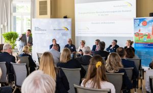 Podiumsdiskussion mit sechs Personen vor Publikum, Leinwand zeigt „Energieeffizienz: Herausforderungen im Bestand", 30. Mai 2023.