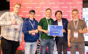 Fünf Personen posieren vor "leanlab"-Banner. Zwei halten ein blaues Schild: "Sonderpreis 1.000 Euro". Alle tragen Namensschilder.
