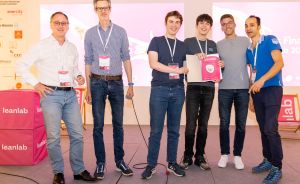 Sechs Männer stehen auf einer Bühne vor einem „leanlab"-Banner, zwei halten Dokumente/Auszeichnungen in der Hand.