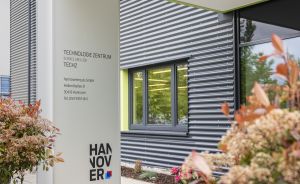Eingangsschild des Technologie Zentrums TECH2 in Hannover mit Adresse, umgeben von Sträuchern und modernem Gebäude.