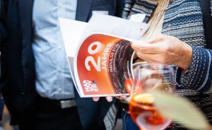 Person hält ein rotes Heft mit der Aufschrift „20 Jahre – Impulse für unseren Standort" der Stadt Hannover.