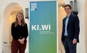 Zwei Personen stehen neben einem Banner mit der Aufschrift „KI.WI – Das KI-Netzwerk der Wirtschaftsregion Hannover".