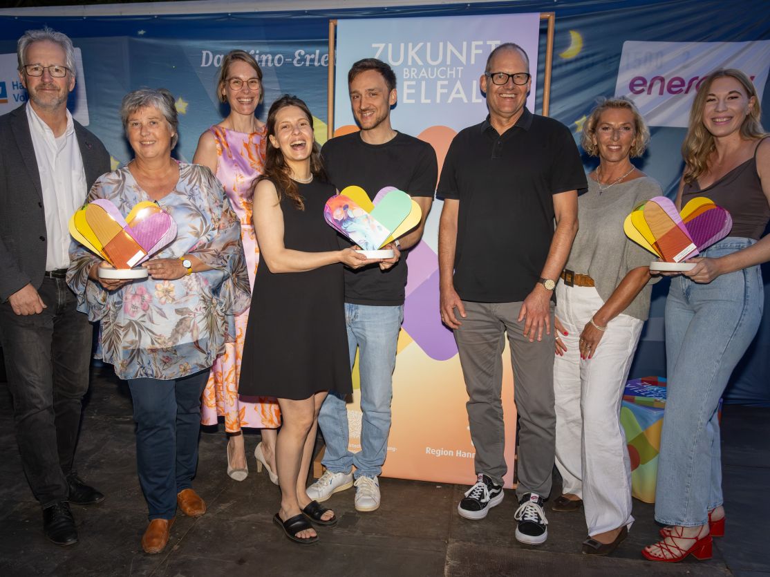 Mehrere Personen freuen sich und halten insgesamt drei Awards in der Hand.