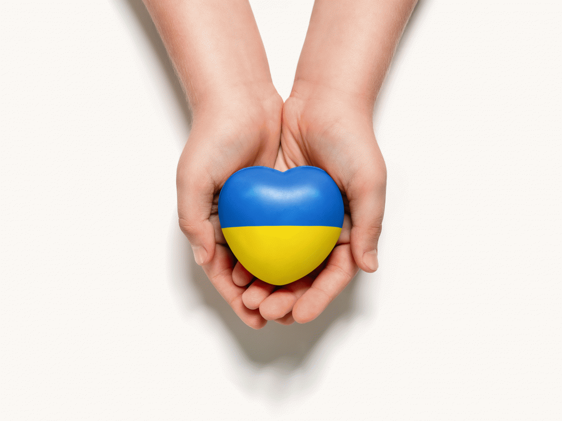 Hände halten Herz mit ukrainischer Flagge