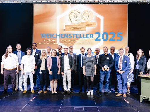 Gruppenfoto von etwa 20 Personen vor einer Leinwand mit der Aufschrift „Weichensteller 2025" bei einer Preisverleihung.